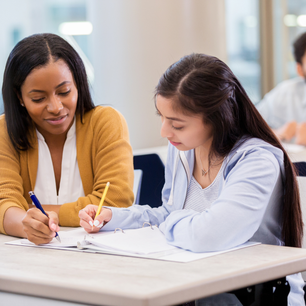 Photo d'un professeur particulier aidant une collégienne à faire ses devoirs