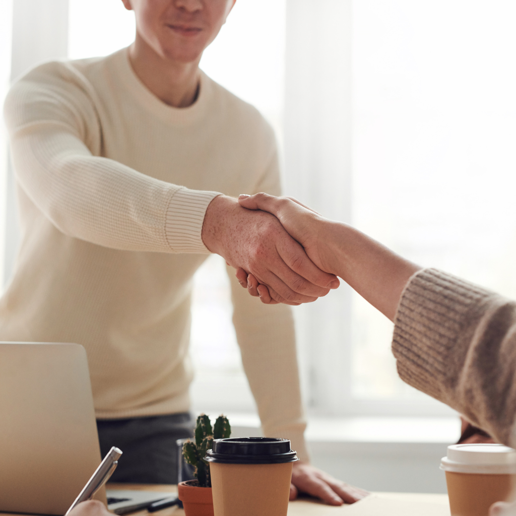 Photo d'un jeune diplômé qui vient de trouver un premier emploi se concrétisant par une poignée de main avec son recruteur